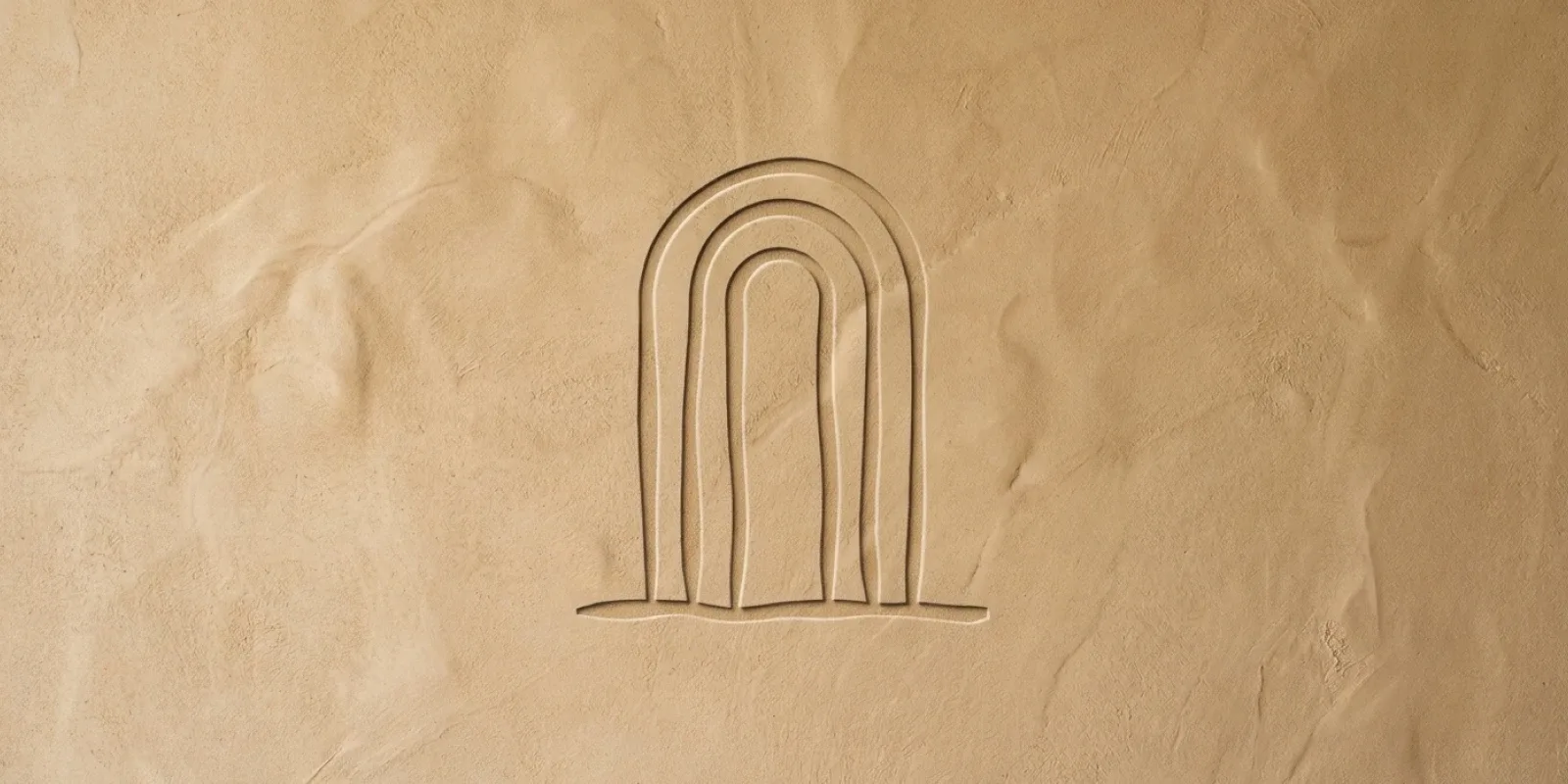 The Mrida mark blind debossed into a hand troweled lime plaster wall in warm sand.
