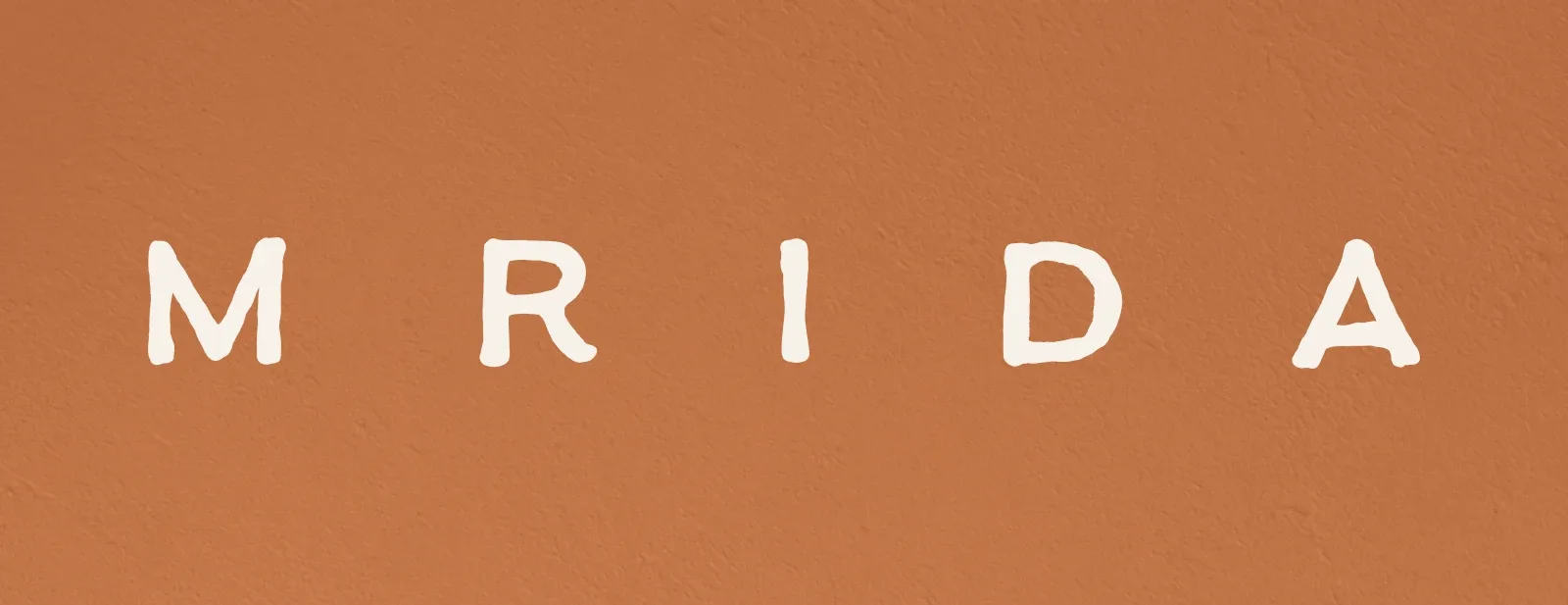 The Mrida wordmark in Chalk on a Clay coloured plaster wall.